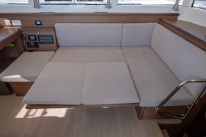 A boat interior with a cushioned seating area, control panels, and a window. - Sun-Kissed Sailing Adventure in the Ionian Islands, Lefkada (Lefkada)