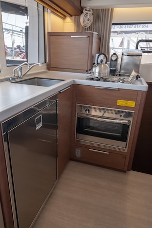A compact kitchen with a stainless steel dishwasher, a built-in oven, and a kettle. - Sun-Kissed Sailing Adventure in the Ionian Islands, Lefkada (Lefkada)