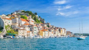 A coastal town with historic buildings, a harbor with boats, and a prominent castle on a hill. - Sibenik Sunshine Sailing: A Luxurious Croatian Beach Experience (Sibenik)