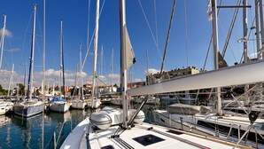 Un port de plaisance où sont amarrés de nombreux bateaux, avec un ciel dégagé et une surface d’eau calme.