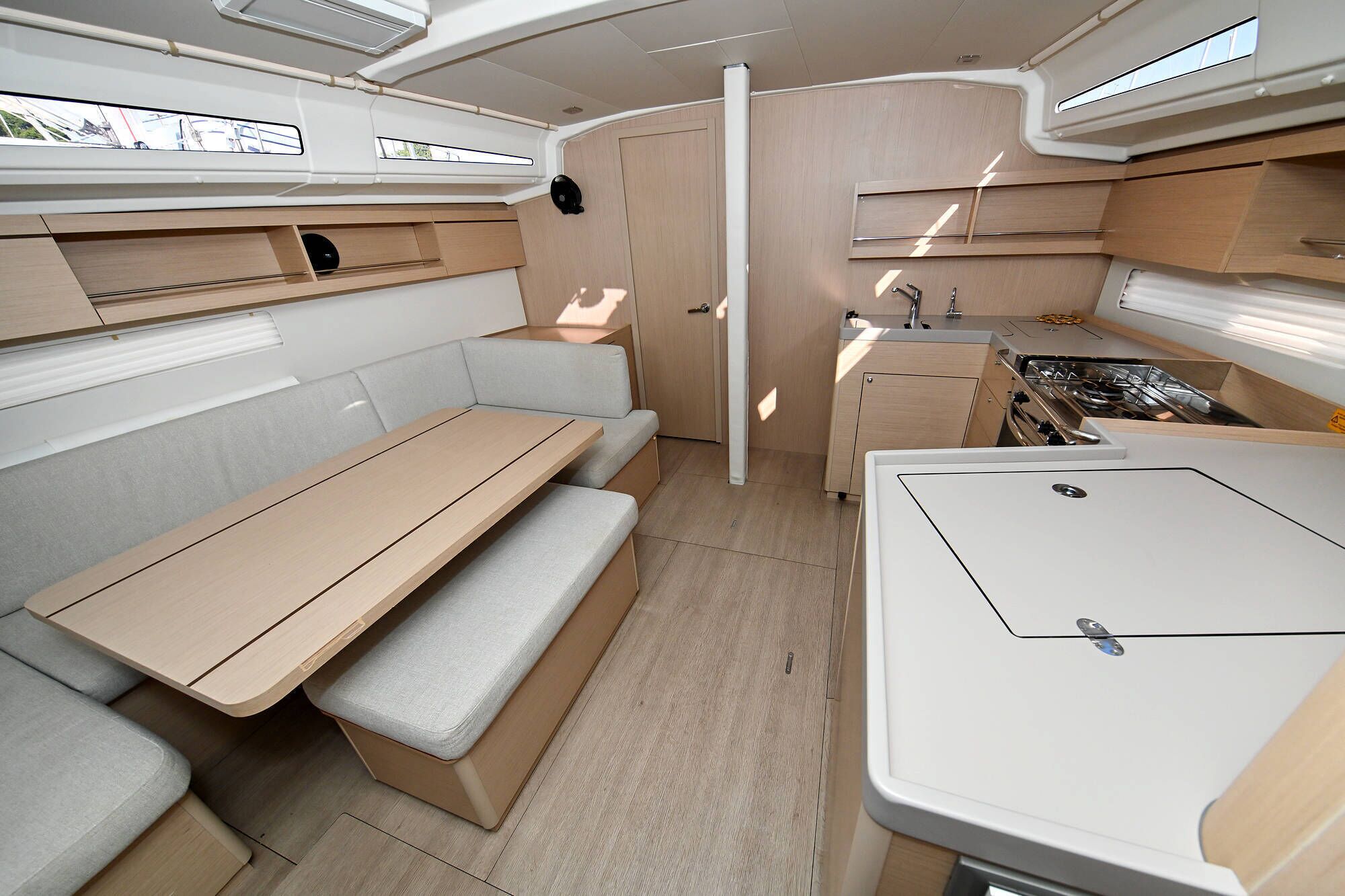 A compact RV interior with a kitchenette, a dining area, and a small seating space.