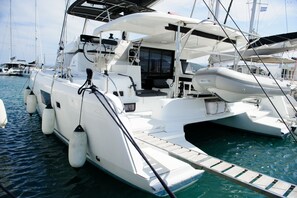 A white yacht docked at a marina with a covered deck area, a seating arrangement, and a small open space for dining. - Sun-Kissed Sailing Adventure in the Ionian Islands, Lefkada (Lefkada)