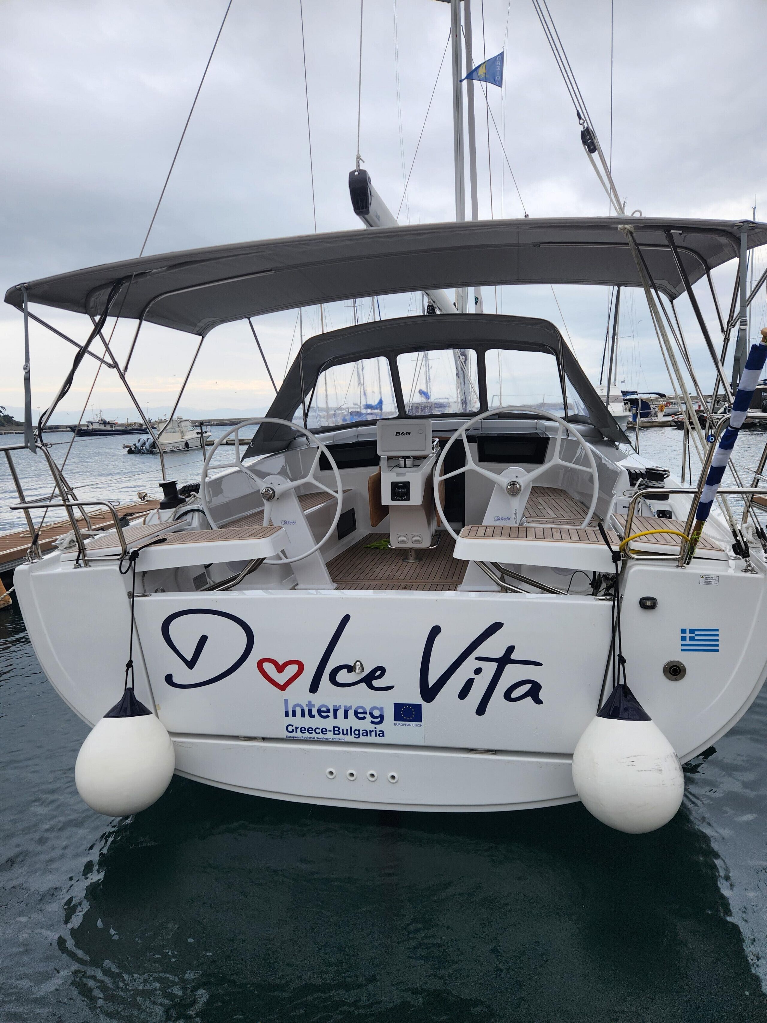 A boat named 'Ice Vita' docked at a marina with a clear view of the water and other boats in the background.
