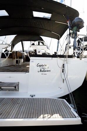 Un bote con un letrero que dice 'Captain Melianos' y una barandilla metálica.
