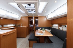 A compact, well-lit interior with a kitchenette, seating area, and a small dining table. - Sun-Kissed Sailing Adventure in the Dodecanese Islands (Kos)