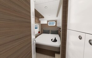 A compact bedroom with a bed, a small window, and a bedside table.
