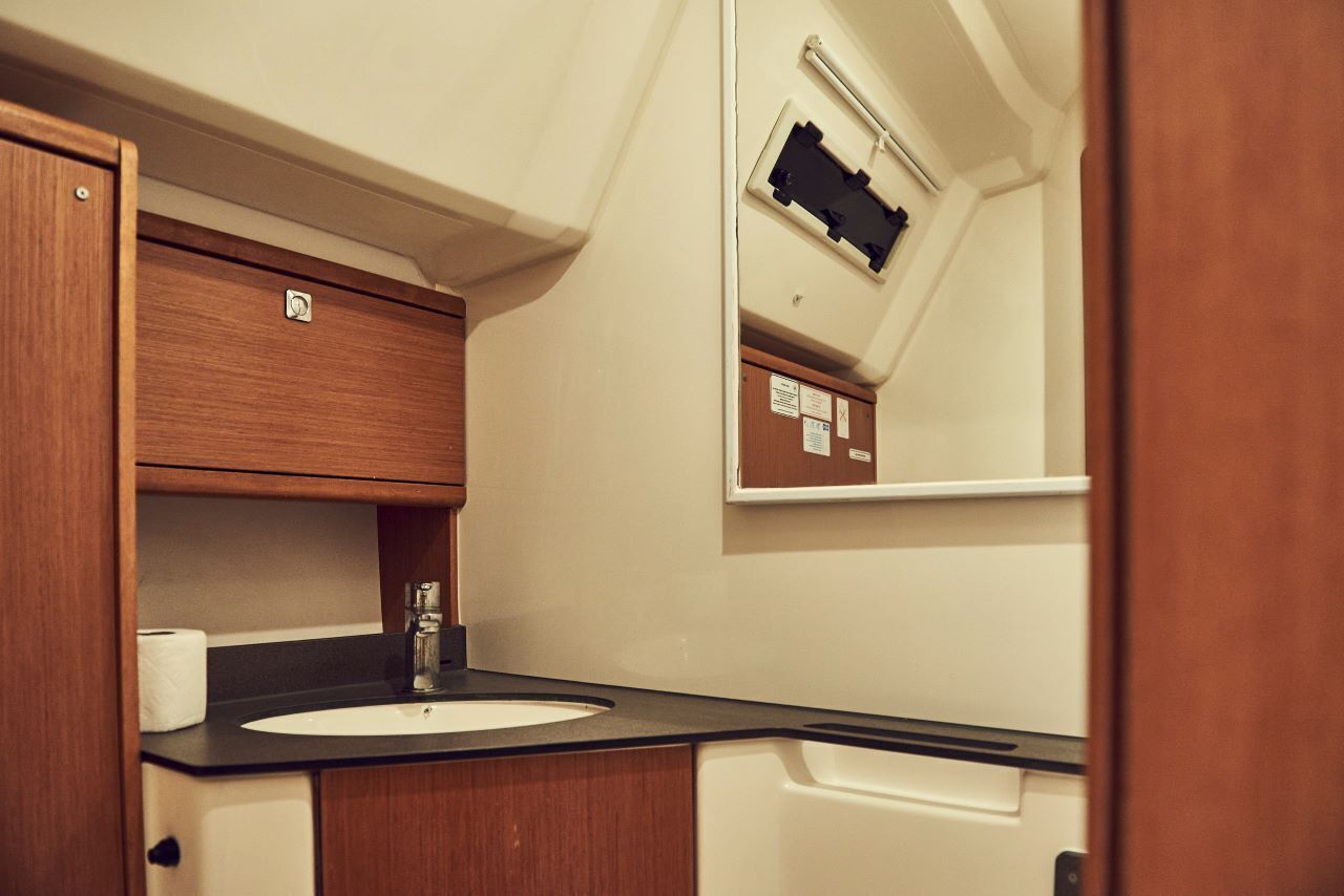 A compact bathroom with a sink, mirror, and wooden cabinets.