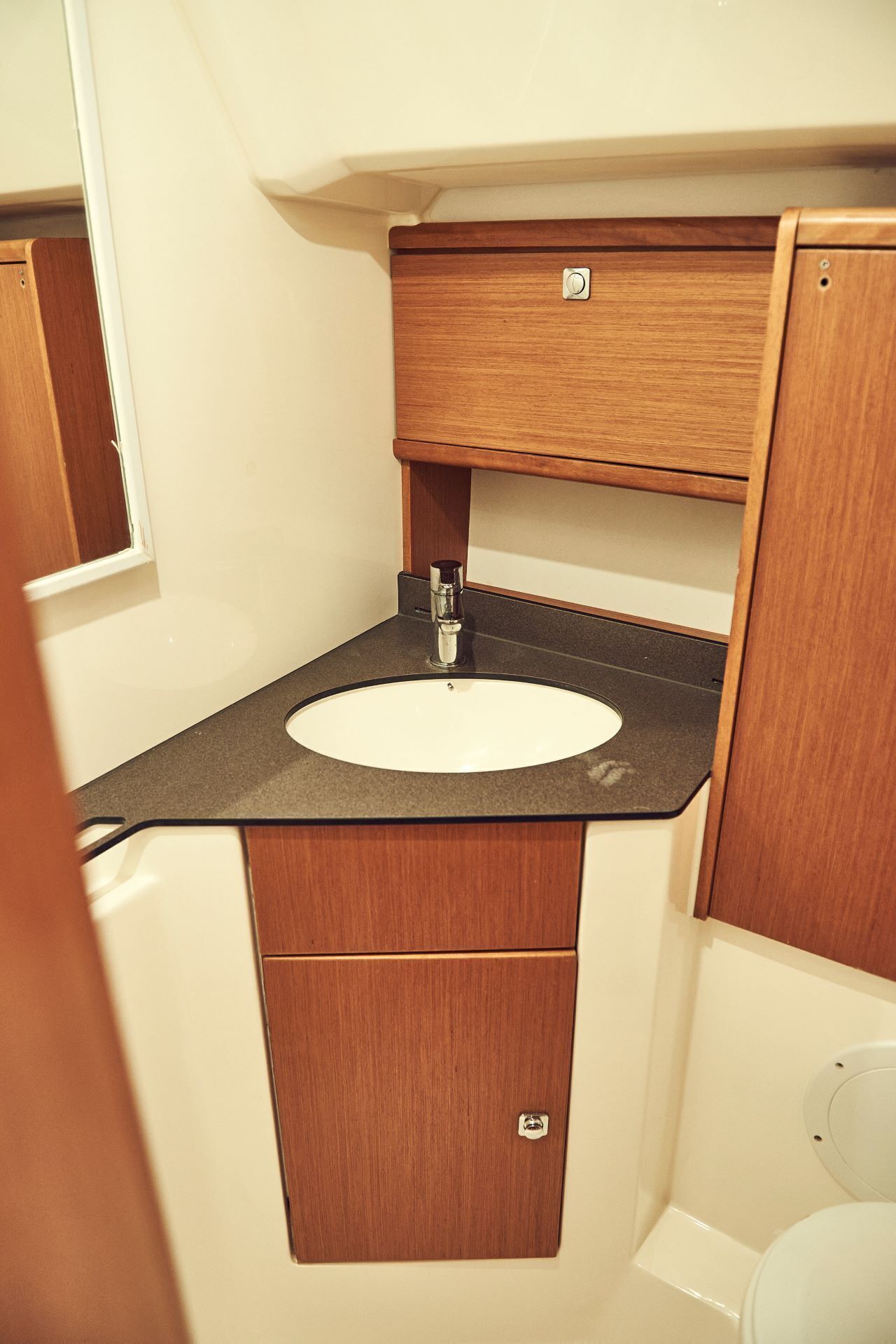 A compact bathroom with a sink, vanity, and toilet.