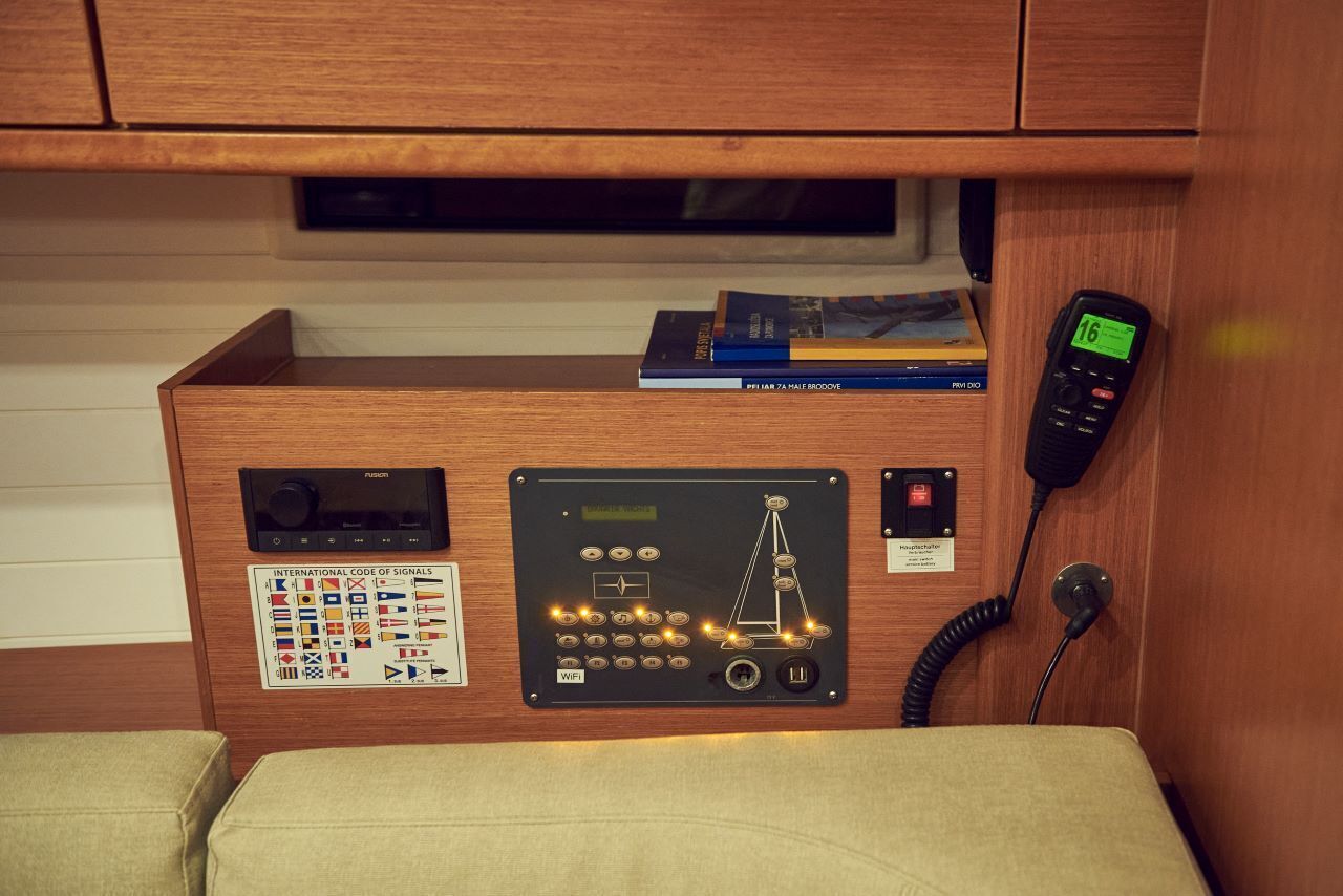 A control panel with various buttons and a display, a telephone, and a book on a shelf.