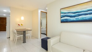 A modern living room with a white sofa, a dining table with chairs, and a painting on the wall. - Sea Residence (Ipojuca)