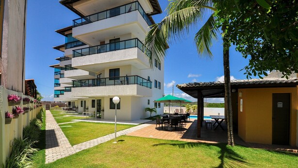 A multi-story building with balconies, a patio area with outdoor furniture, and a pool. - Sea Residence (Ipojuca)