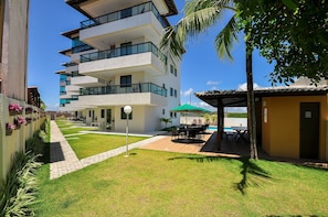 Ein mehrstöckiges Gebäude mit Balkonen, einer Terrasse und Gartenmöbeln sowie einem Pool.