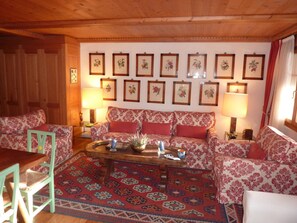 Ein gemütliches Wohnzimmer mit einer Sofagarnitur, einem Couchtisch und gerahmten floralen Kunstwerken an der Wand.