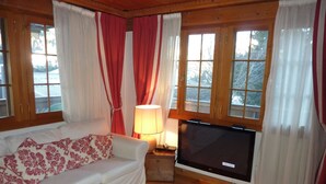 Ein gemütliches Wohnzimmer mit einem weißen Sofa, einem Flachbildfernseher und Holzböden.