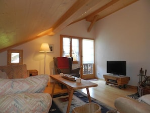 A cozy living room with a sofa, a table, a television, and a chair. - Im Wiesengrund Appartement/Fewo, Dusche oder Bad, WC 4-Bettwohnung by Interhome (Gstaad)