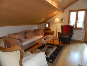A cozy living room with a sofa, a chair, a small table, and a lamp. - Im Wiesengrund Appartement/Fewo, Dusche oder Bad, WC 4-Bettwohnung by Interhome (Gstaad)