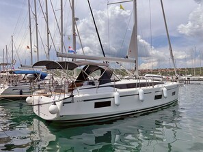 A white yacht docked at a marina with multiple masts and flags.