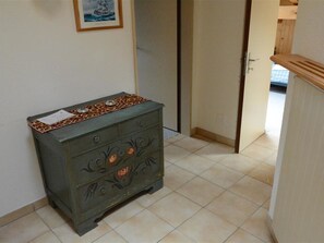 Una habitación con un aparador pegado a la pared, una puerta que da a otra estancia y un piso de baldosas.
