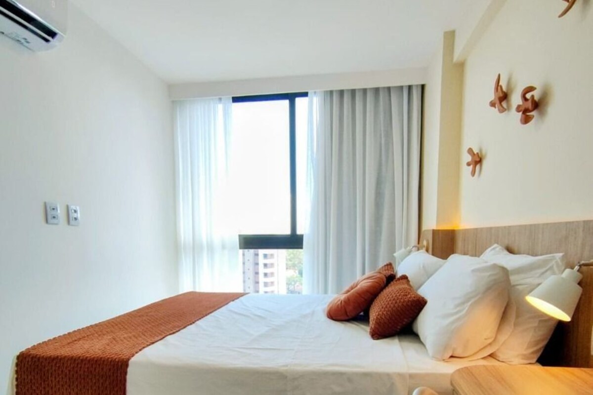 Ein Hotelzimmer mit Bett, Nachttisch und Blick ins Freie.