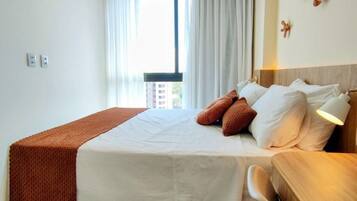 Habitación de hotel con cama, mesita de noche y vistas al exterior.