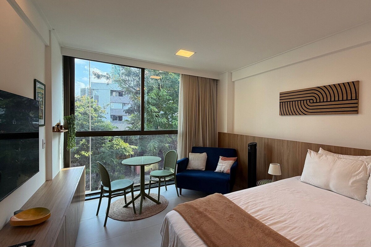 Habitación de hotel con cama, escritorio, silla, mesa y televisor.