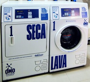 A front view of a white laundry machine with 'SECA' and 'LAVA' labels, and the 'OMO' logo.