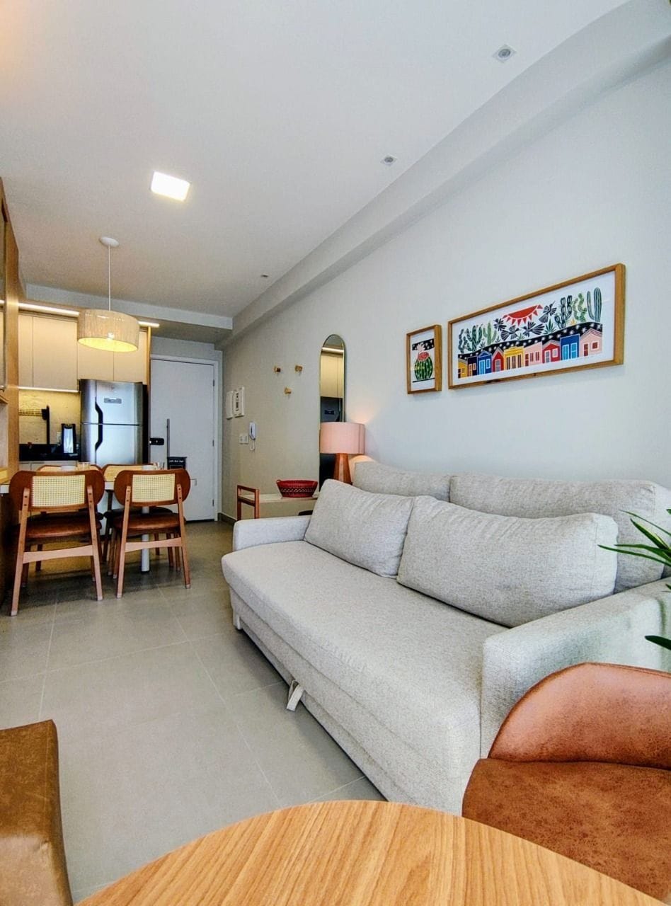 A modern living room with a sofa, dining table, chairs, and a kitchen area.