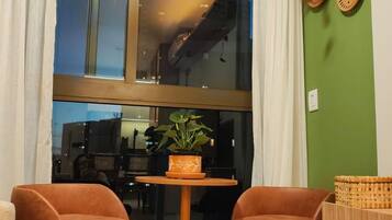 A room with a large window, two chairs, a small table, a potted plant, and decorative wall plates.