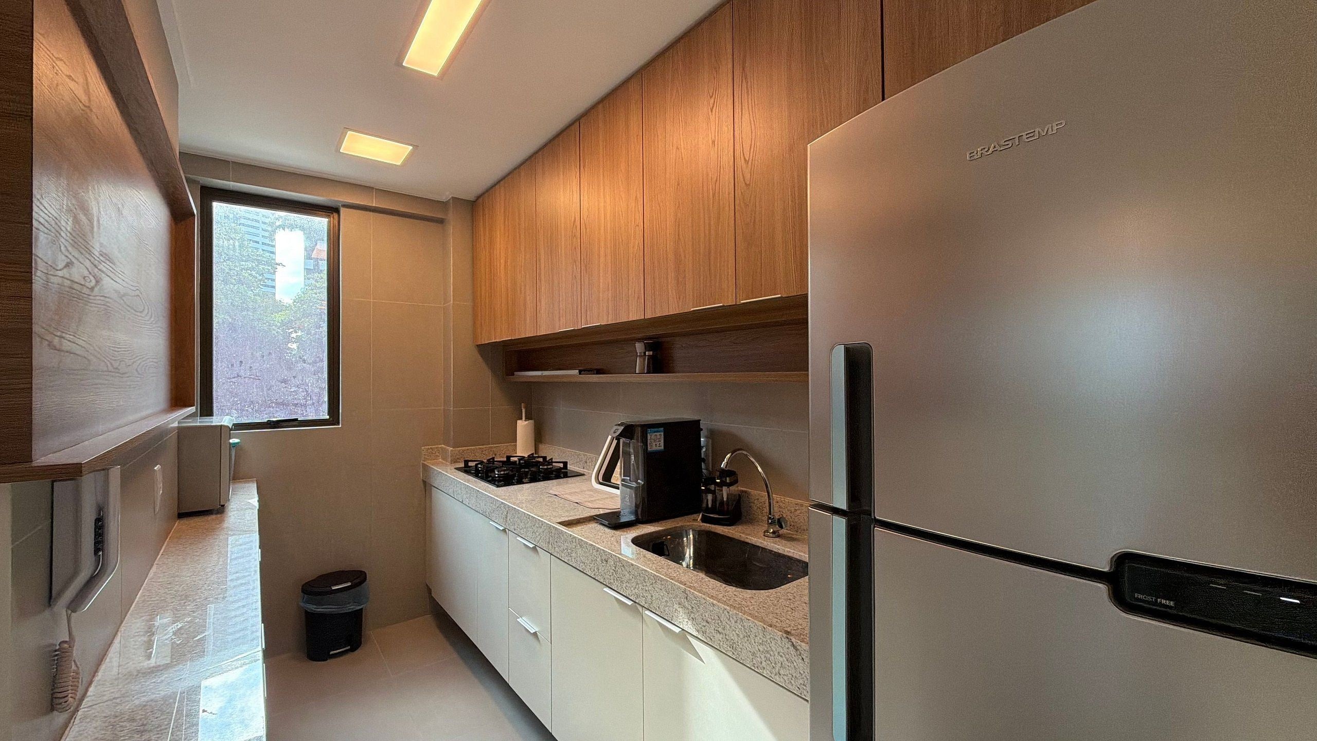 Una cocina moderna con gabinetes de madera, un refrigerador de acero inoxidable, una estufa a gas y un lavamanos.