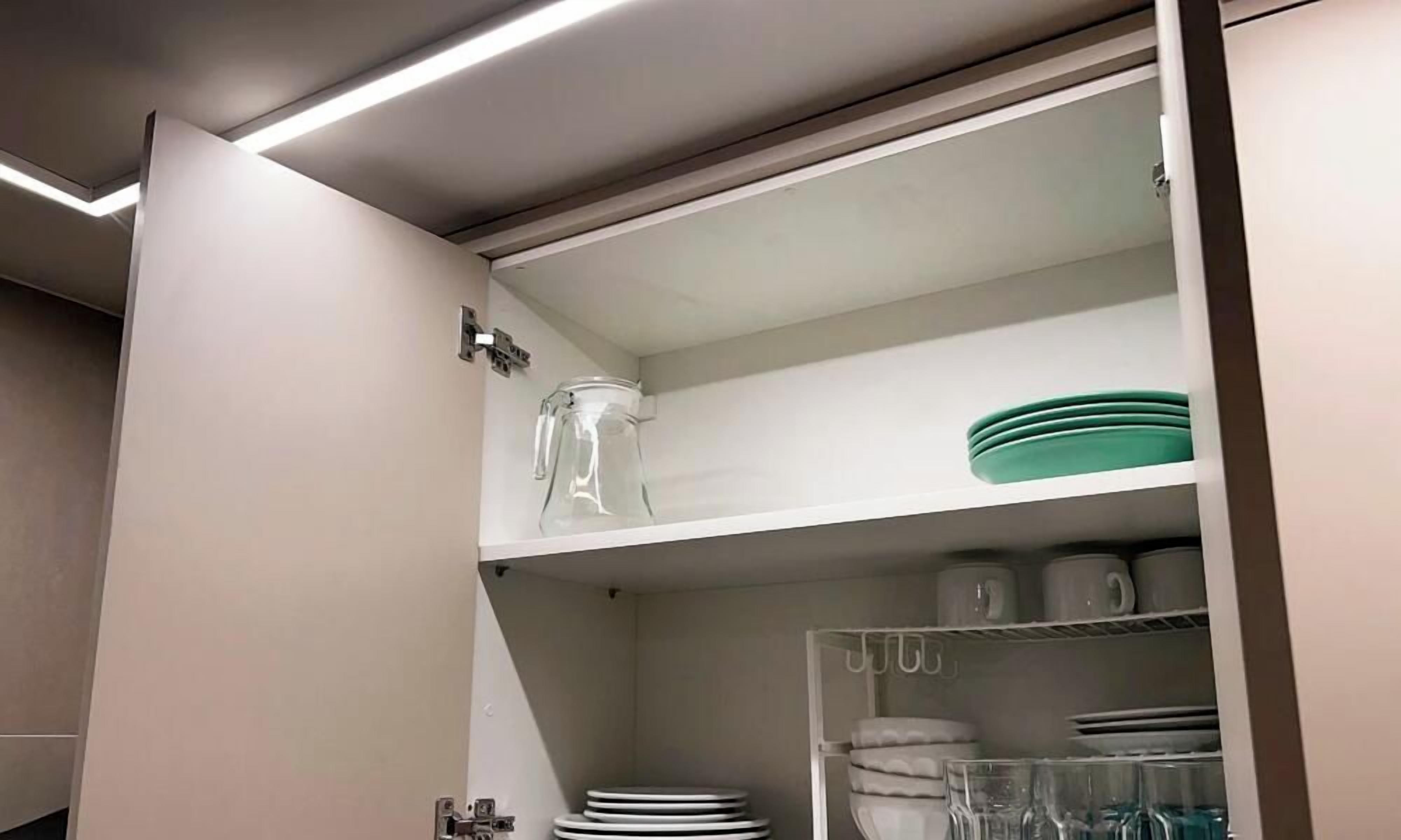 Una cocina con estante empotrado que contiene una jarra de vidrio, platos y tazones.