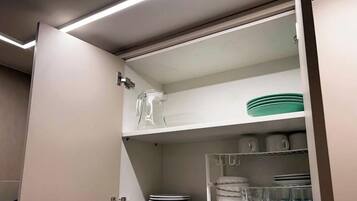 Una cocina con estante empotrado que contiene una jarra de vidrio, platos y tazones.