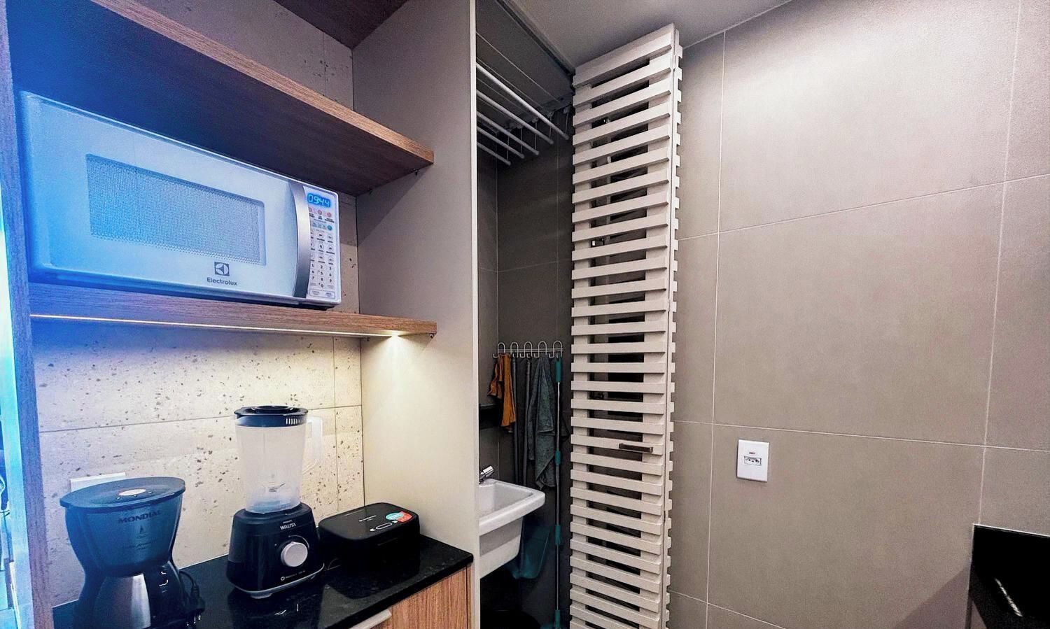 Cocina compacta con microondas, licuadora y cafetera sobre la encimera.