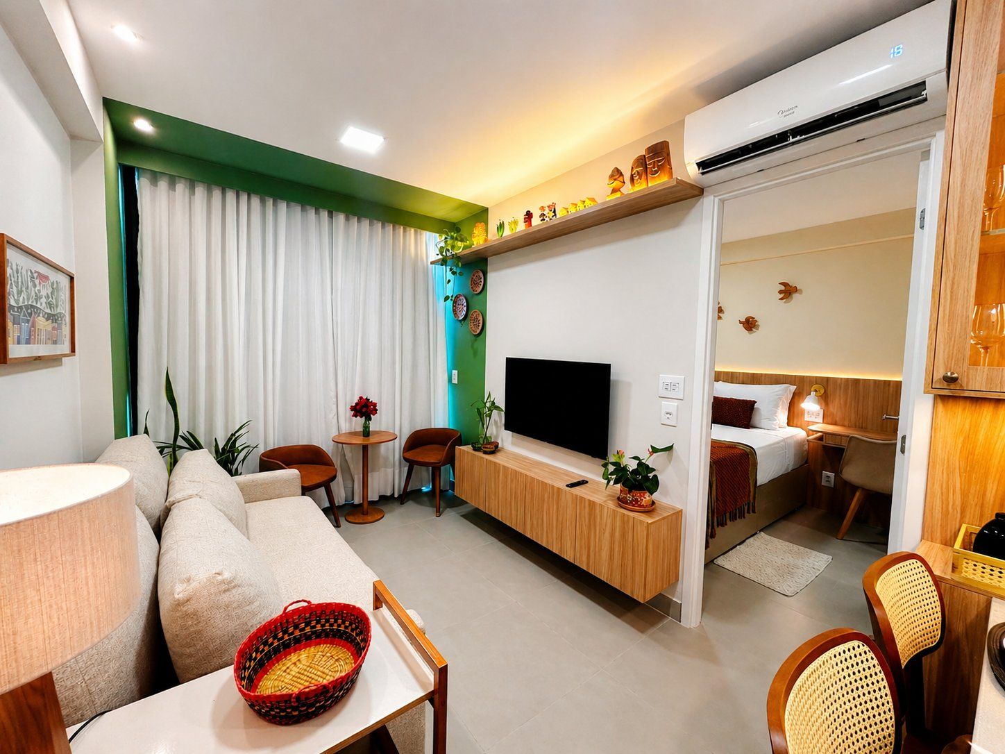 Quarto de hotel moderno com sofá, mesa de jantar, televisão e área de dormir separada.