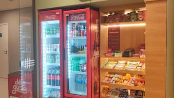 A Redmart store with three Coca-Cola refrigerators and a variety of snacks and beverages on shelves.