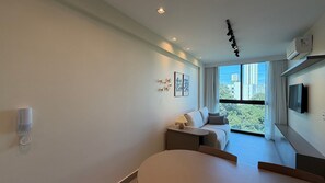 A modern living room with a sofa, a coffee table, and a TV mounted on the wall. - Casa Forte Prince por Yolo (Recife)