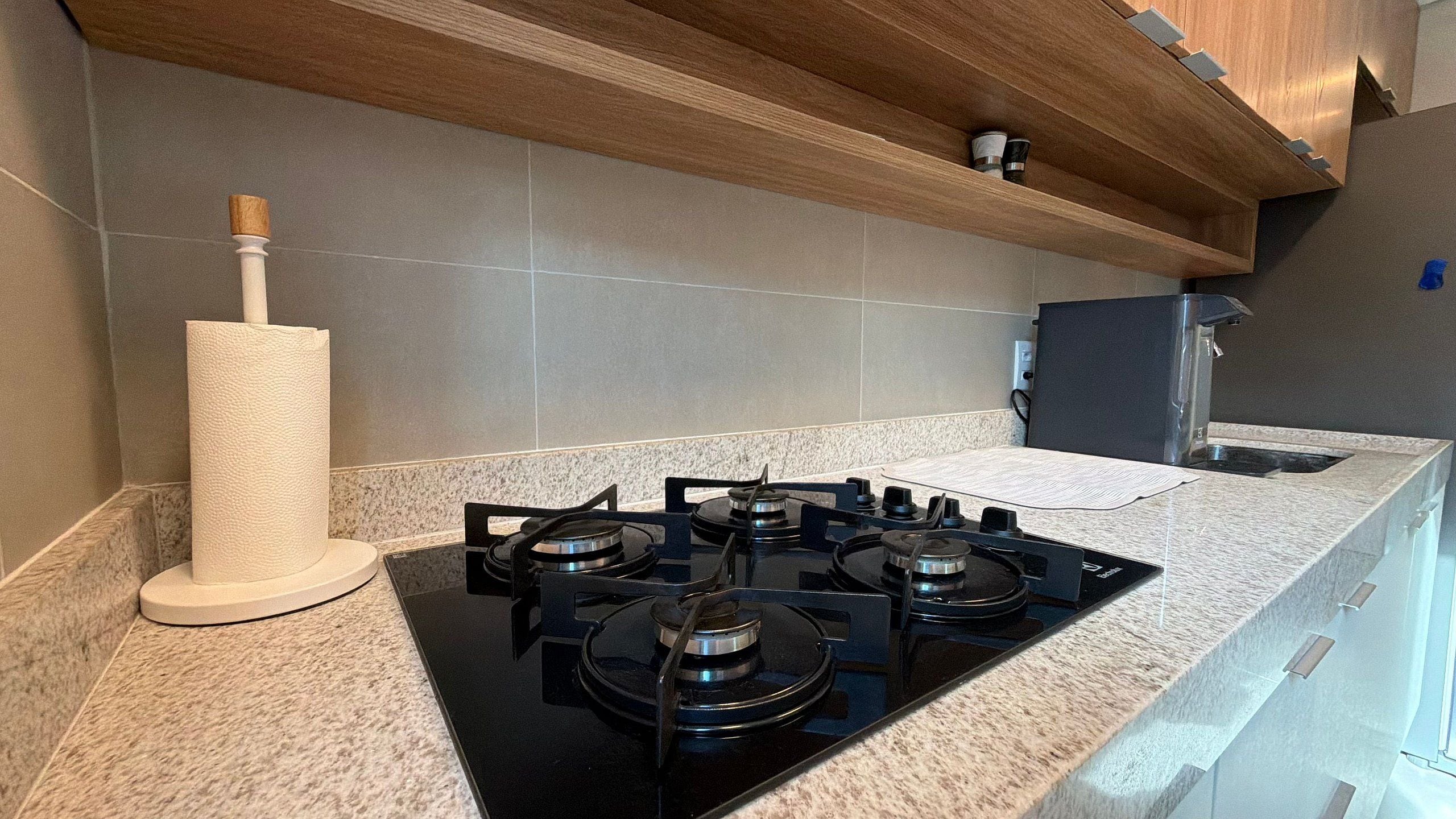 Una cocina con estufa a gas, dispensador de toallas de papel y refrigerador.