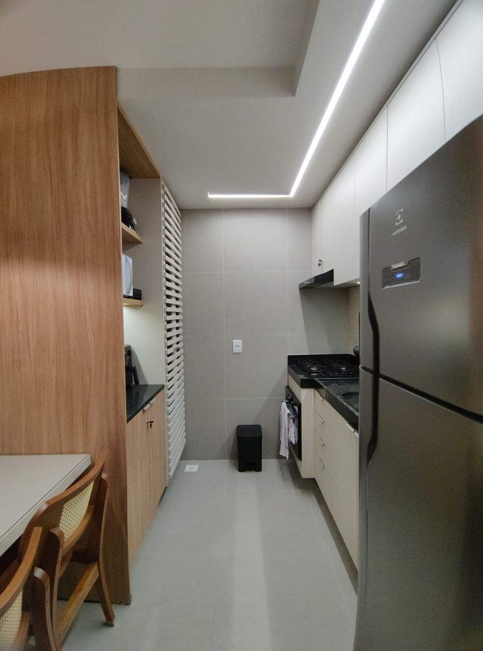 Una cocina compacta con refrigerador integrado, estufa y comedor con mesa y sillas.