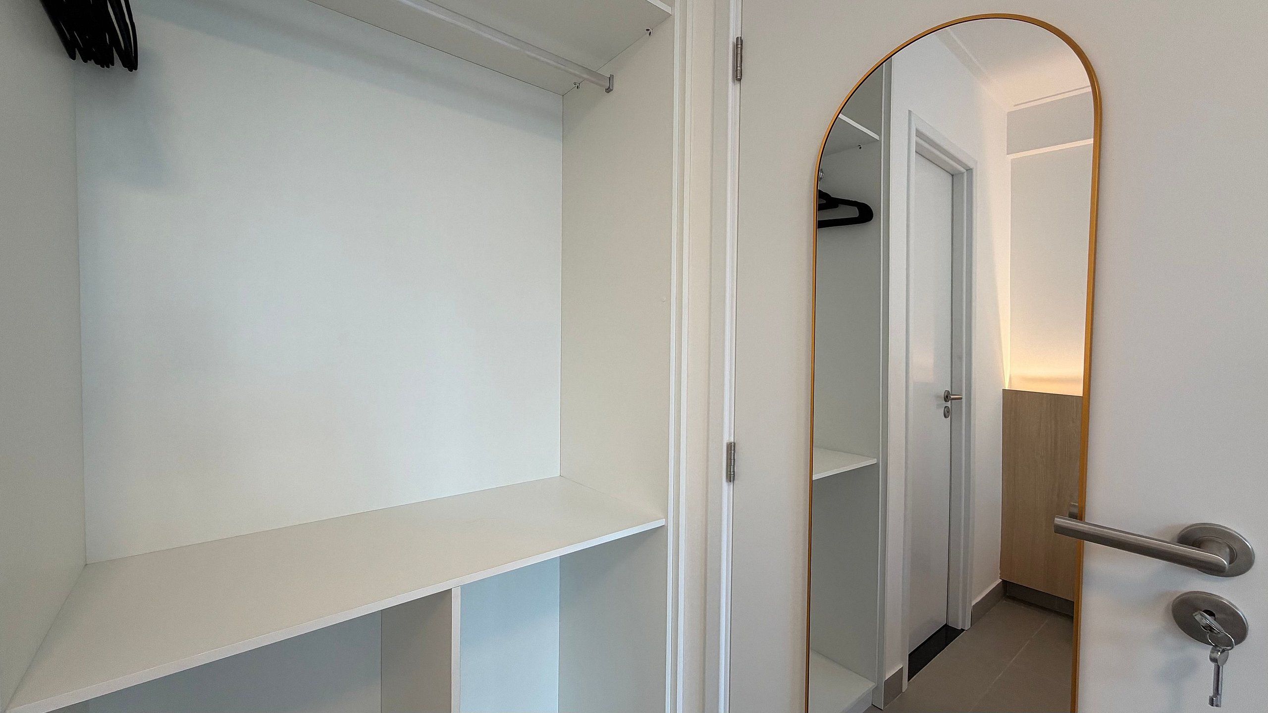 A hallway with a white door, a coat rack, and a mirror.