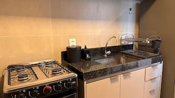 Une cuisine équipée d’une cuisinière à gaz, d’un évier et d’une machine à café.