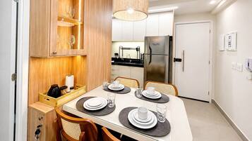 A modern kitchen with a built-in refrigerator, wooden cabinetry, and a dining area set for four with placemats and cutlery.