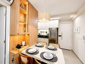 Eine moderne Küche mit Einbaukühlschrank, Holzschränken und einem Essbereich für vier Personen, gedeckt mit Platzsets und Besteck.
