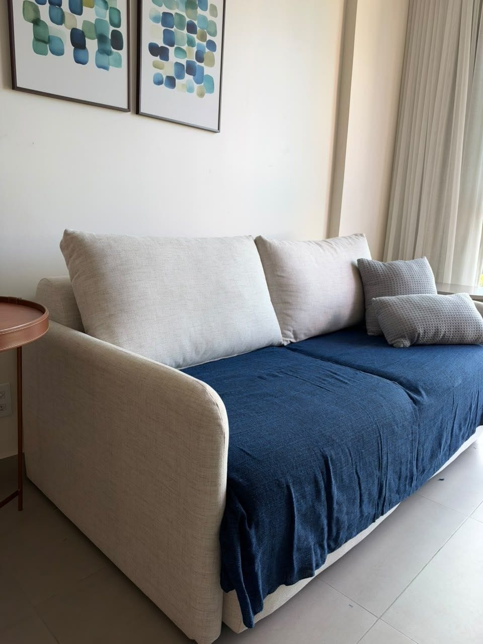 A modern living room with a sofa, pillows, and a small round table.
