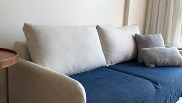 A modern living room with a sofa, pillows, and a small round table.