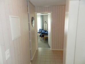 A hallway with a door on the left, a mirror on the wall, and a room with a bed and a chair in the background. - Monique Nr. 14 Appartement/Fewo, Dusche oder Bad, WC 5-Bettwohnung by Interhome (Gstaad)