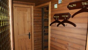 Een houten interieur met een deur, een metalen hekwerk en een kapstok aan de muur.