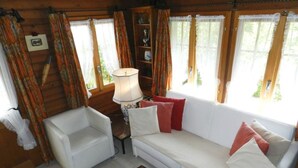 Een gezellige kamer met een witte bank, een kleine witte stoel en een lamp.