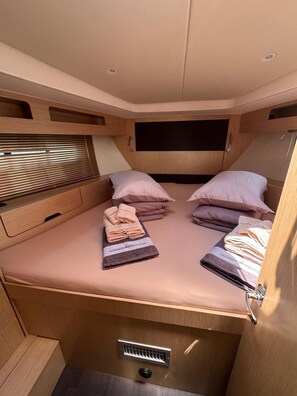 Ein kleiner, helles Zimmer mit Bett, Kissen und Handtüchern.