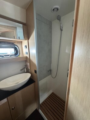 Een kleine badkamer met een wastafel, spiegel en douche.