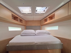 A compact, modern bedroom with a bed, skylights, and built-in storage.