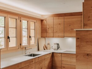 A modern kitchen with wooden cabinets, a stainless steel sink, and a countertop. - Giferblick Appartement/Fewo, Dusche und Bad, WC 6-Bettwohnung by Interhome (Gstaad)